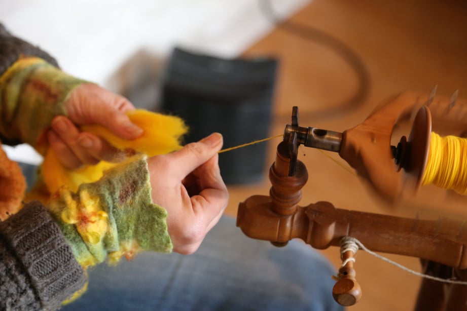 Hände und Garn mit Spinnrad