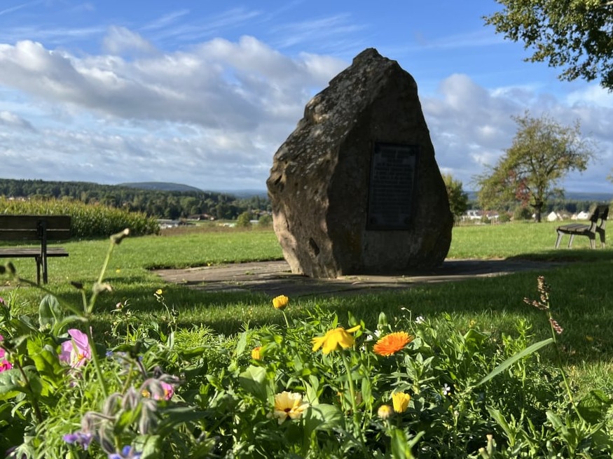 Waldenserstein von hinten mit Blumen und Sonnenschein