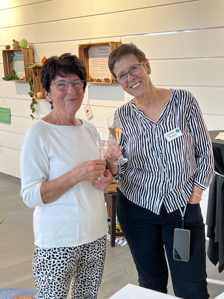 Zwei lächelnde Besucherinnen mit Sektglas